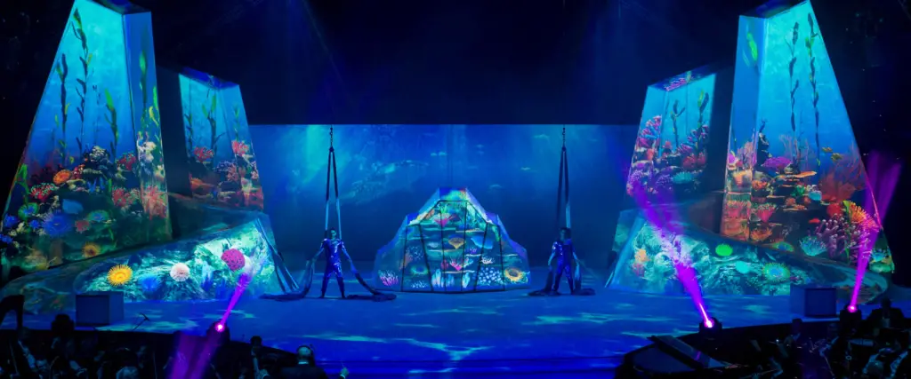 Futuristic underwater-themed stage show with vibrant lights and performers.